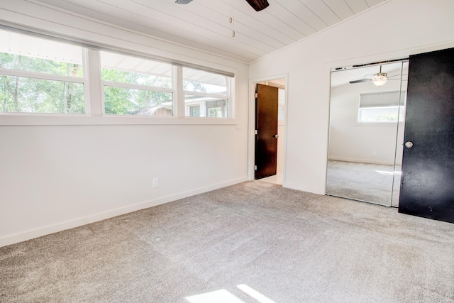 unfurnished bedroom with ceiling fan, vaulted ceiling, light carpet, and multiple windows