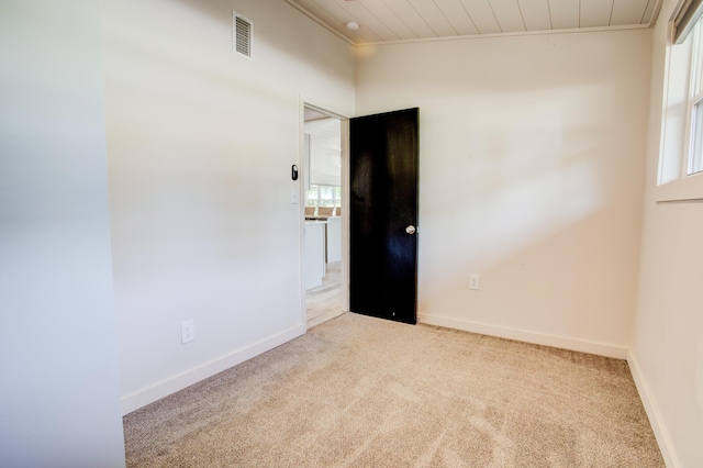 carpeted spare room featuring wood ceiling and ornamental molding