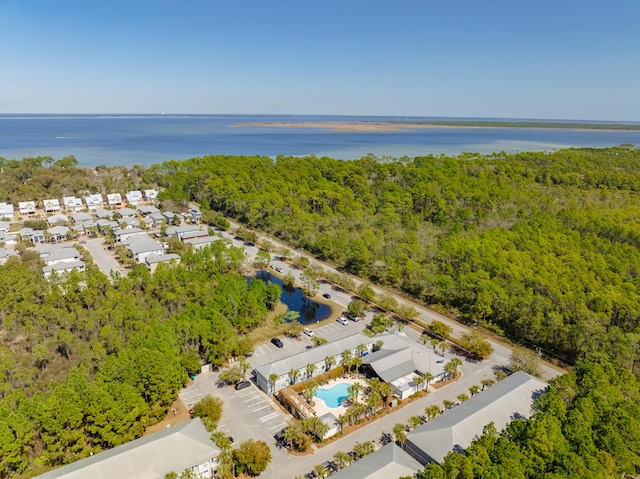 drone / aerial view with a wooded view and a water view