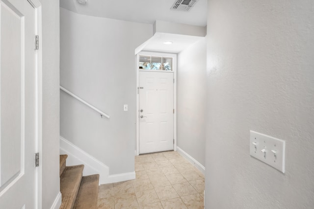 foyer entrance featuring light tile patterned floors, visible vents, stairway, and baseboards