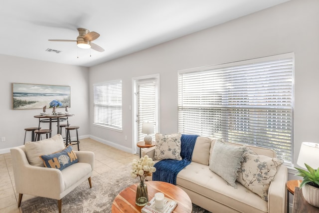 living room with light tile patterned floors, visible vents, baseboards, and ceiling fan