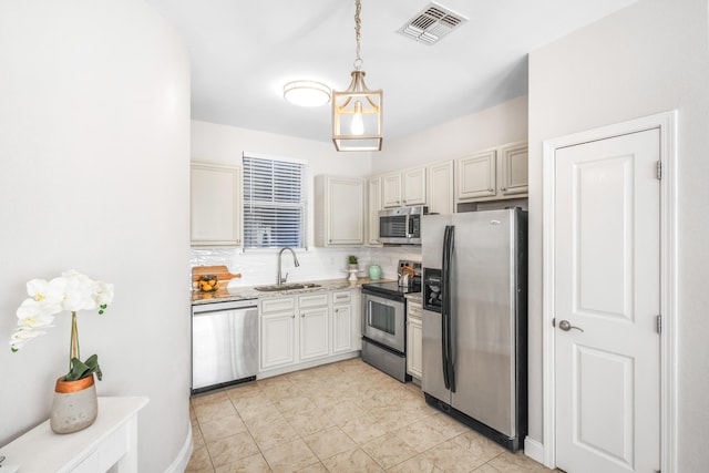 kitchen featuring visible vents, pendant lighting, a sink, tasteful backsplash, and stainless steel appliances