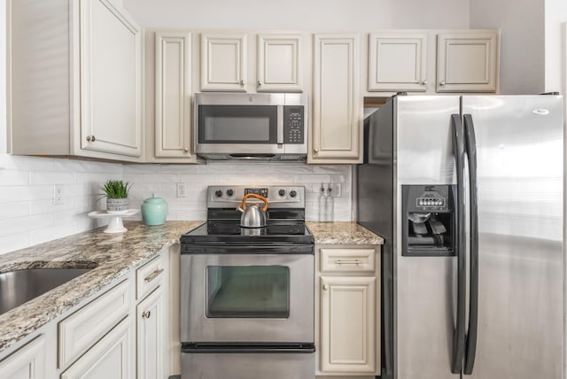 kitchen featuring stainless steel appliances, light stone countertops, and decorative backsplash