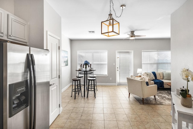 living area featuring a wealth of natural light, light tile patterned floors, baseboards, and ceiling fan