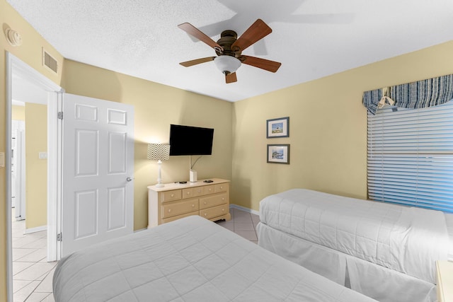 tiled bedroom with ceiling fan and a textured ceiling