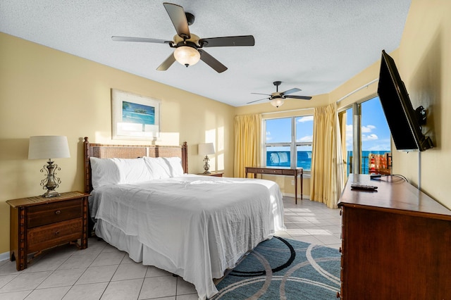 bedroom featuring ceiling fan, light tile patterned floors, and a textured ceiling