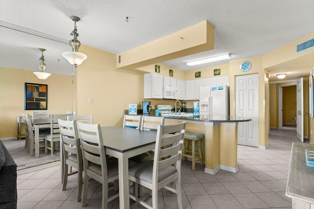 dining area featuring sink, a textured ceiling, and light tile patterned flooring