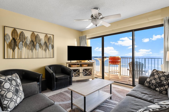 living room featuring ceiling fan, light tile patterned flooring, and a textured ceiling