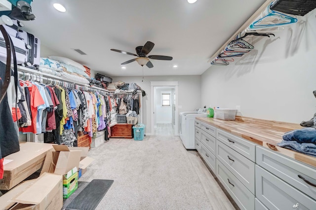 spacious closet featuring ceiling fan, washer and dryer, and light hardwood / wood-style flooring