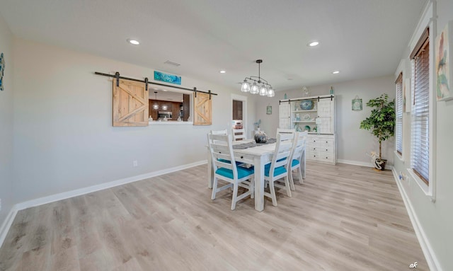 dining space featuring a barn door and light hardwood / wood-style flooring