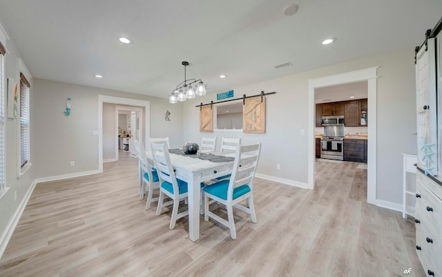 dining space with light wood-type flooring and a barn door