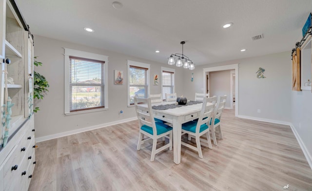 dining space featuring a barn door and light wood-type flooring