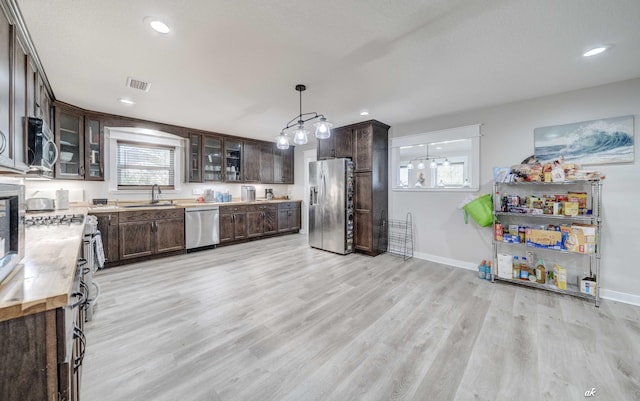 248 Sukoshi Dr, Panama City, FL 32404 - kitchen featuring stainless steel appliances, dark brown cabinetry, light wood finished floors, light countertops, and plenty of natural light