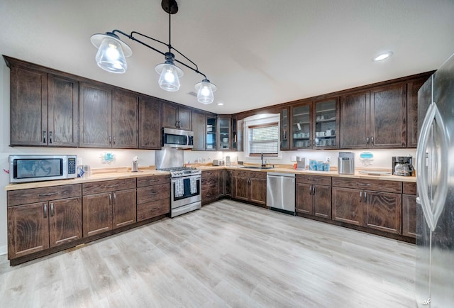 kitchen with stainless steel appliances, hanging light fixtures, sink, and dark brown cabinetry