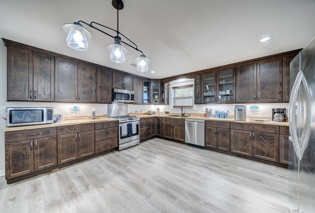 248 Sukoshi Dr, Panama City, FL 32404 - kitchen featuring stainless steel appliances, a sink, dark brown cabinets, hanging light fixtures, and light wood-type flooring