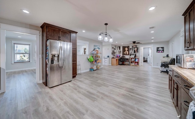 kitchen with appliances with stainless steel finishes, hanging light fixtures, dark brown cabinets, and light hardwood / wood-style flooring