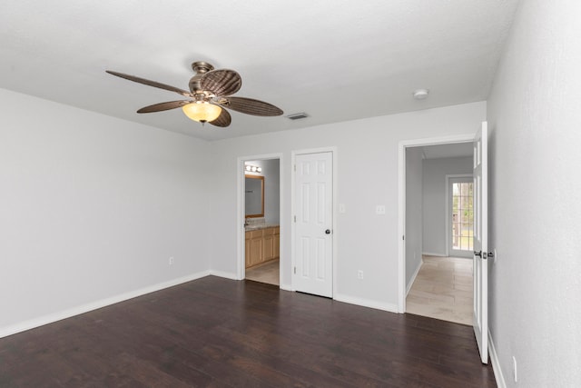 unfurnished bedroom featuring dark wood-type flooring, ceiling fan, and ensuite bath