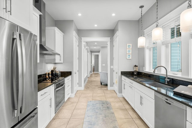 kitchen with white cabinetry, sink, appliances with stainless steel finishes, dark stone countertops, and hanging light fixtures