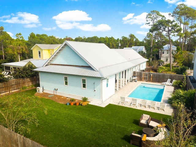 back of house with a fenced in pool, a patio, and a lawn