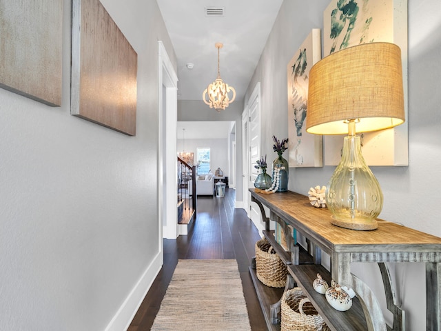 corridor featuring dark hardwood / wood-style flooring and a notable chandelier