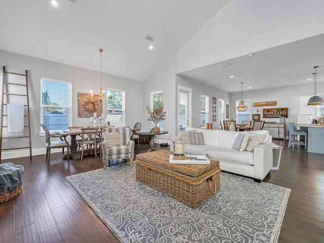 living room with high vaulted ceiling, a wealth of natural light, a notable chandelier, and dark hardwood / wood-style floors