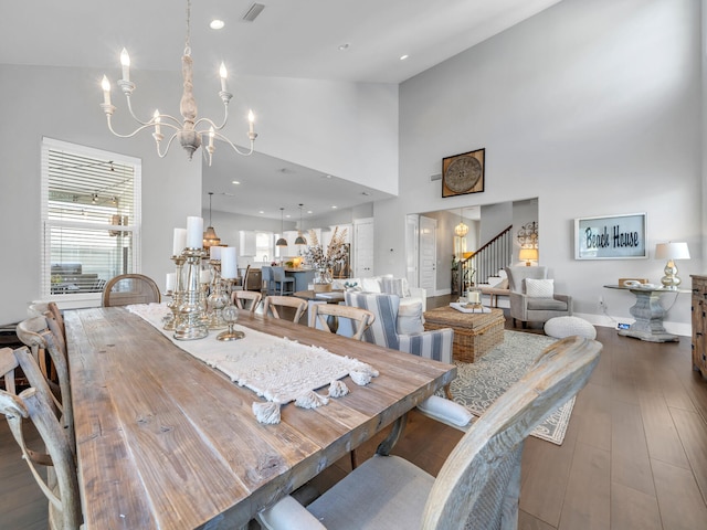 dining space with wood-type flooring, a chandelier, and high vaulted ceiling