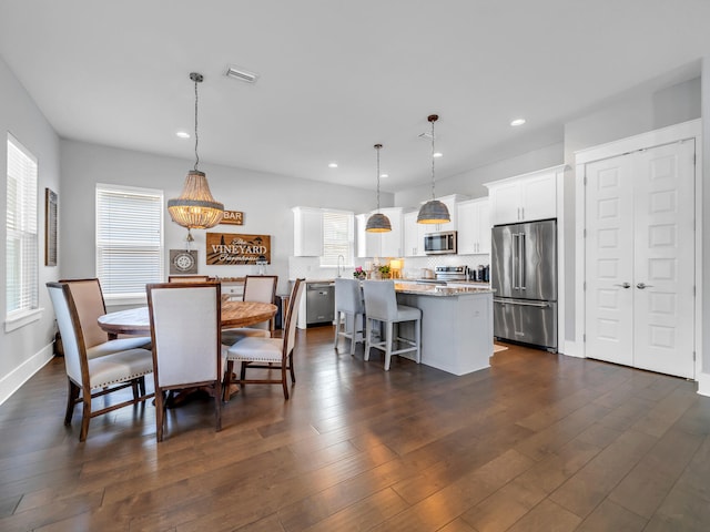 dining room featuring dark wood-type flooring, a wealth of natural light, and a notable chandelier