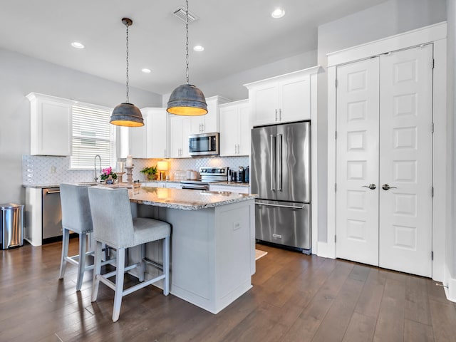 kitchen with dark hardwood / wood-style flooring, a kitchen island, white cabinets, and stainless steel appliances