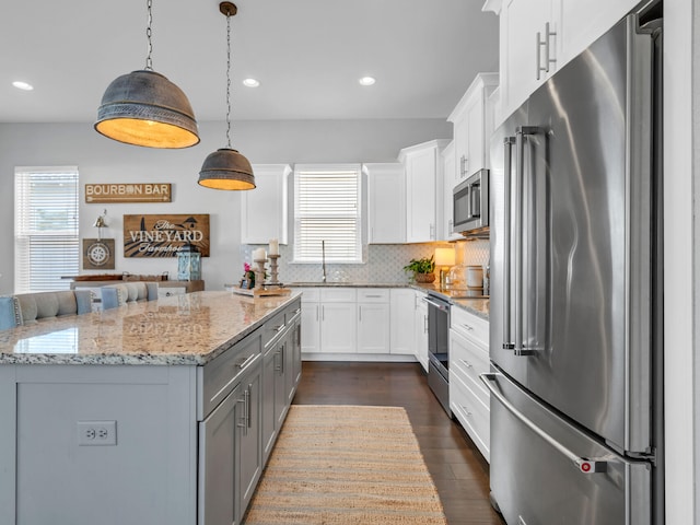 kitchen with stainless steel appliances, dark hardwood / wood-style floors, white cabinets, and decorative light fixtures