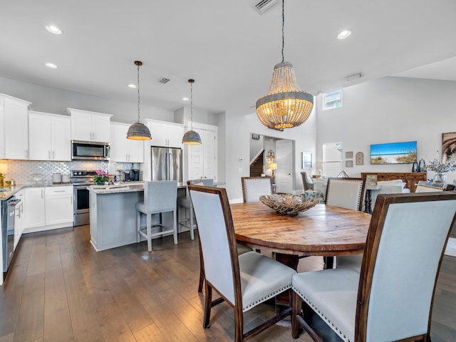 dining space with dark hardwood / wood-style flooring, high vaulted ceiling, and an inviting chandelier