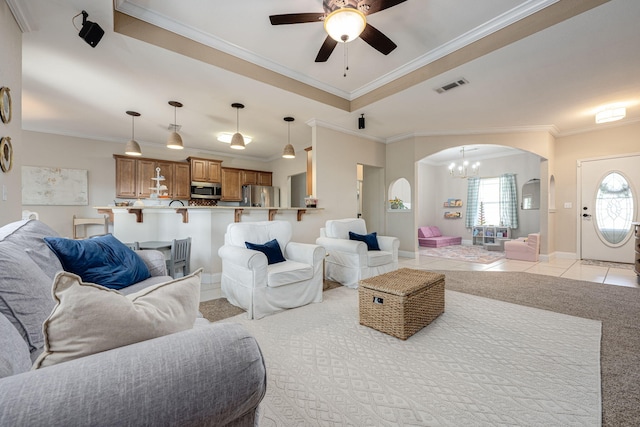 living room featuring ceiling fan with notable chandelier, light colored carpet, and crown molding