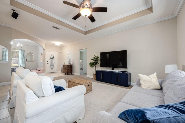 living room with ceiling fan with notable chandelier and crown molding