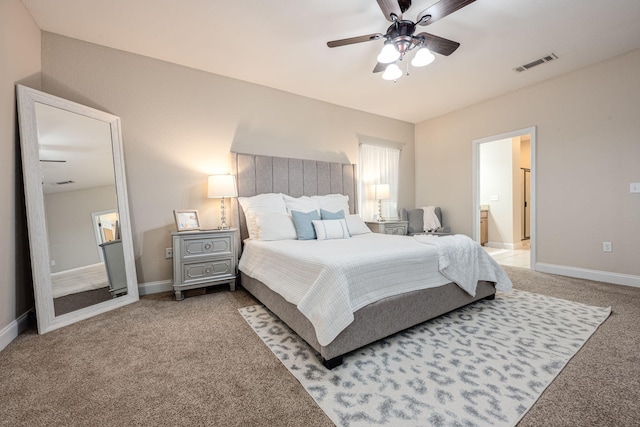 bedroom with ensuite bath, light carpet, and ceiling fan