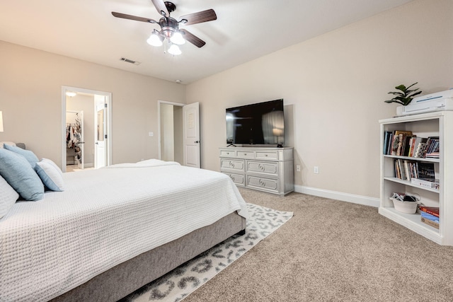 bedroom featuring light carpet, ceiling fan, a walk in closet, and a closet