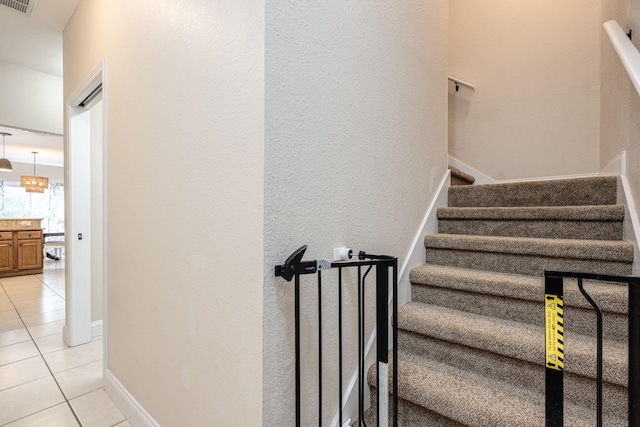 staircase with a chandelier and tile patterned flooring