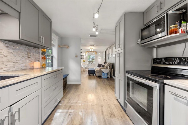 kitchen with light hardwood / wood-style flooring, tasteful backsplash, gray cabinetry, rail lighting, and appliances with stainless steel finishes