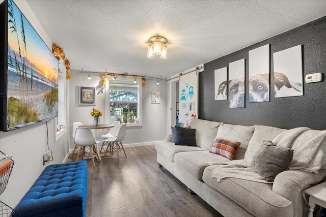 living room featuring a barn door, hardwood / wood-style flooring, and a textured ceiling