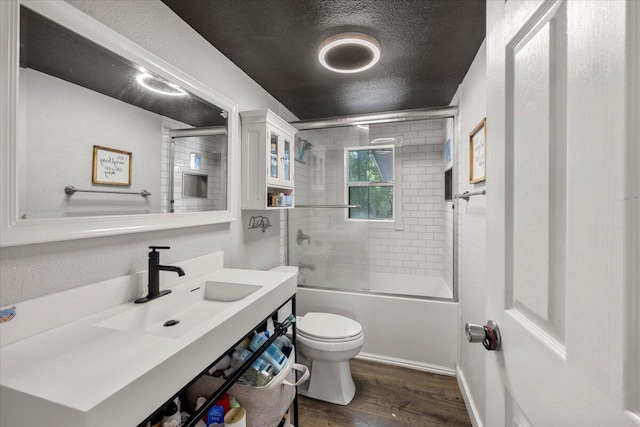 full bathroom with a textured ceiling, shower / bath combination with glass door, wood-type flooring, vanity, and toilet