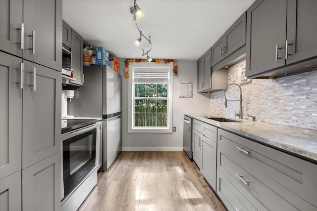 kitchen featuring stainless steel appliances, light hardwood / wood-style floors, sink, tasteful backsplash, and gray cabinetry