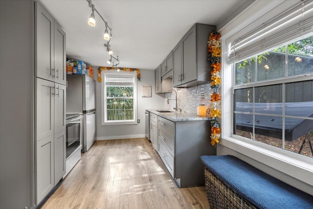 kitchen featuring gray cabinetry, appliances with stainless steel finishes, decorative backsplash, sink, and light hardwood / wood-style floors