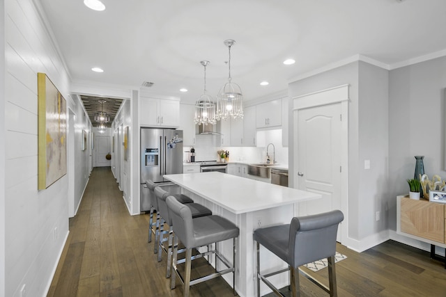 kitchen featuring appliances with stainless steel finishes, hanging light fixtures, a center island, white cabinets, and dark wood-type flooring