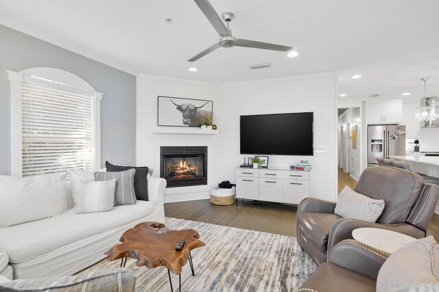 living room featuring ceiling fan with notable chandelier, dark hardwood / wood-style floors, and a fireplace