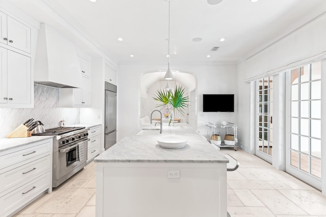 kitchen featuring sink, high end appliances, decorative light fixtures, white cabinets, and premium range hood