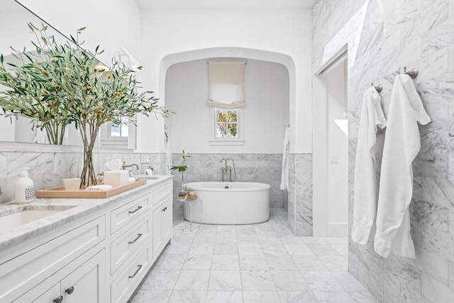 bathroom with tile walls, a bath, and vanity