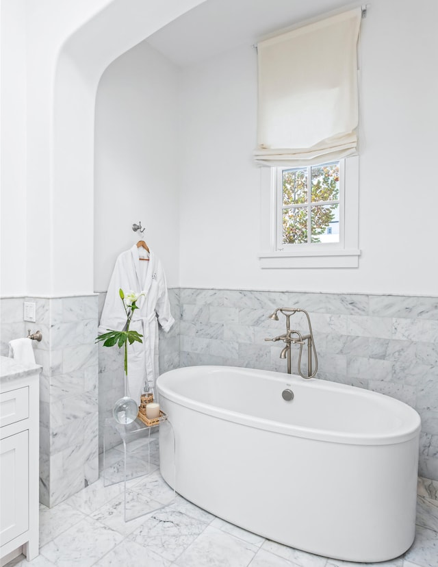 bathroom featuring tile walls, a washtub, and vanity