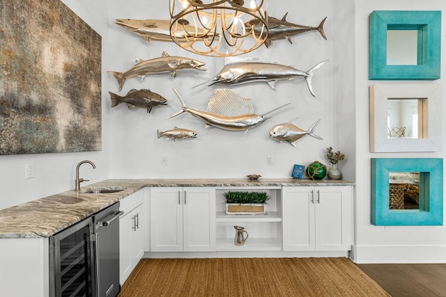 bar with sink, hanging light fixtures, dark wood-type flooring, wine cooler, and white cabinets