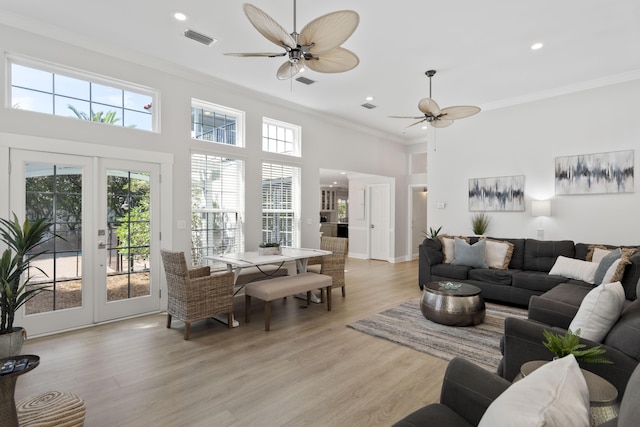 living room with a wealth of natural light, light hardwood / wood-style floors, french doors, and ornamental molding