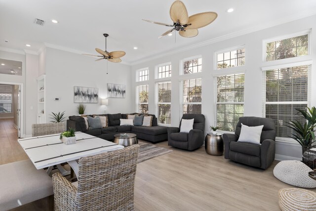 living room with light hardwood / wood-style floors, built in features, crown molding, and ceiling fan