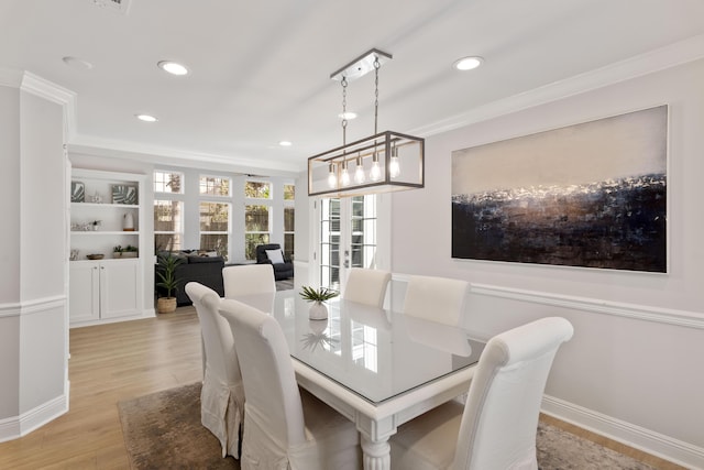 dining area with built in shelves, ornamental molding, and light wood-type flooring