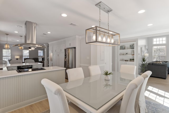 dining room with ornamental molding, light hardwood / wood-style floors, and built in shelves